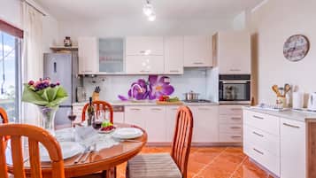 Una cocina moderna con armarios blancos, una mesa de comedor con platos, vasos y un florero.