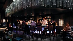 A bar area with a curved counter, multiple seating options, and hanging crystal chandeliers. - One Bedroom Residential Suite at The Sebastian Vail (Vail)