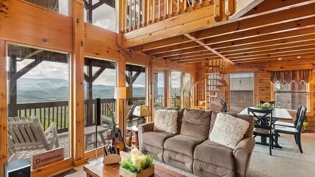 A wooden cabin interior with a sofa, dining table, and chairs. - Majestic 2BD near TOWN! VIEWS + Pool (Pigeon Forge)
