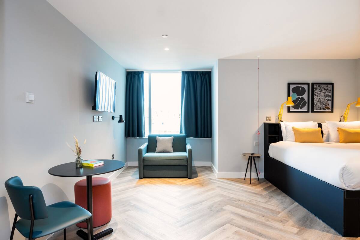 Une chambre d’hôtel moderne équipée d’un lit, d’un bureau, d’une chaise et d’une petite table.