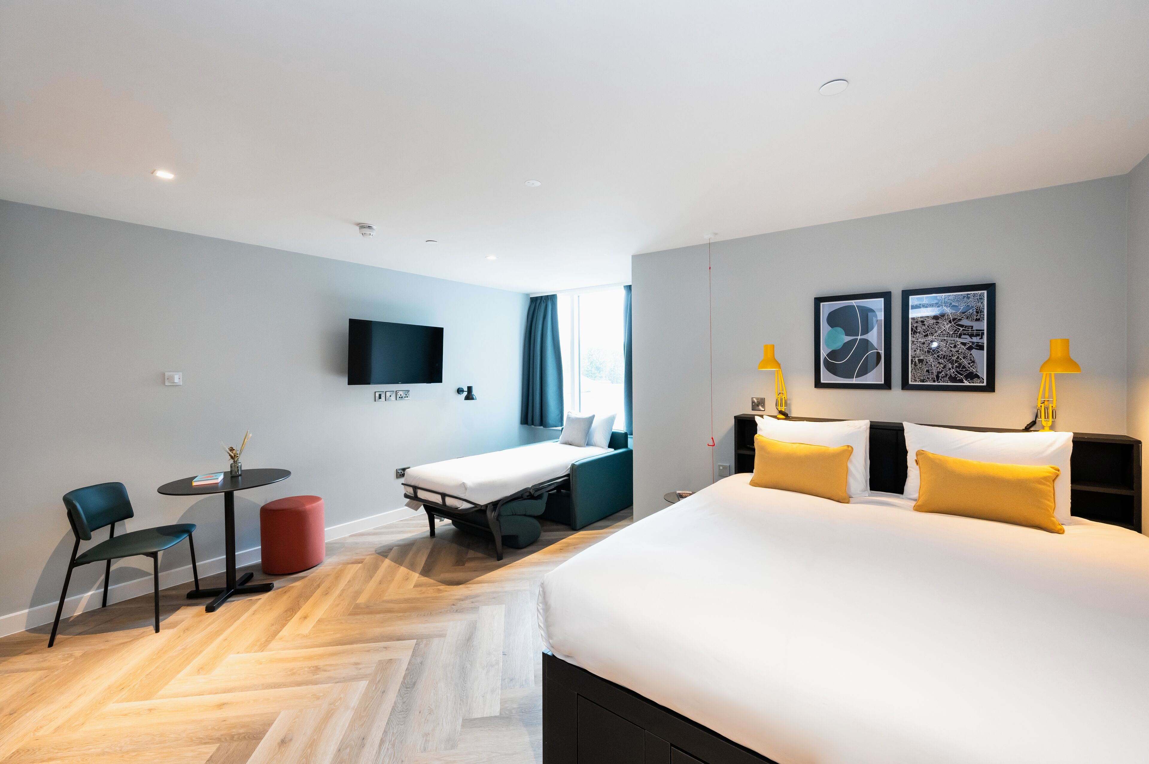 A hotel room with a large bed, a desk, a chair, and a TV.