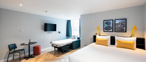 A hotel room with a large bed, a desk, a chair, and a TV.