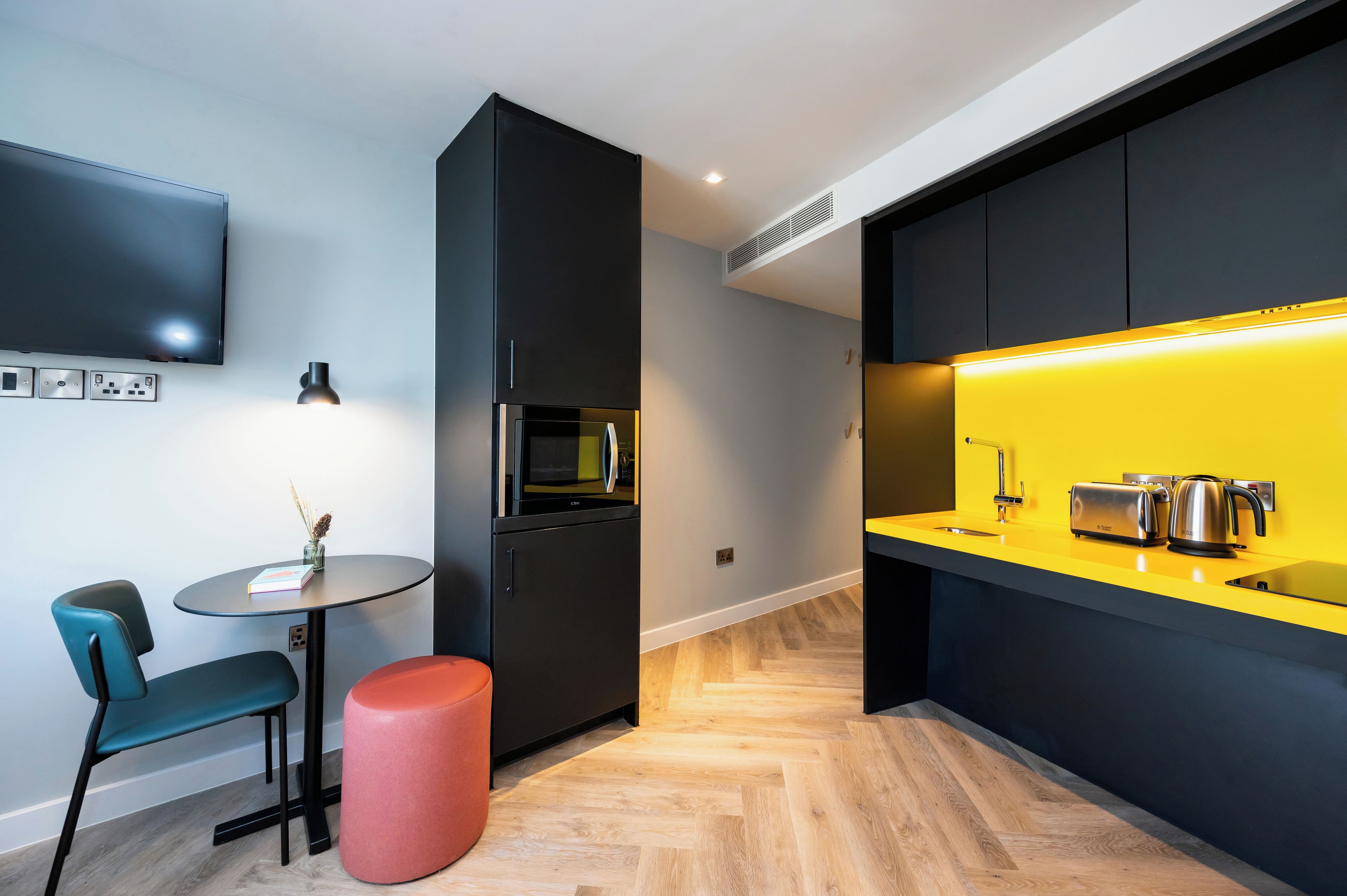 A modern kitchen with a black refrigerator, microwave, and yellow countertop.