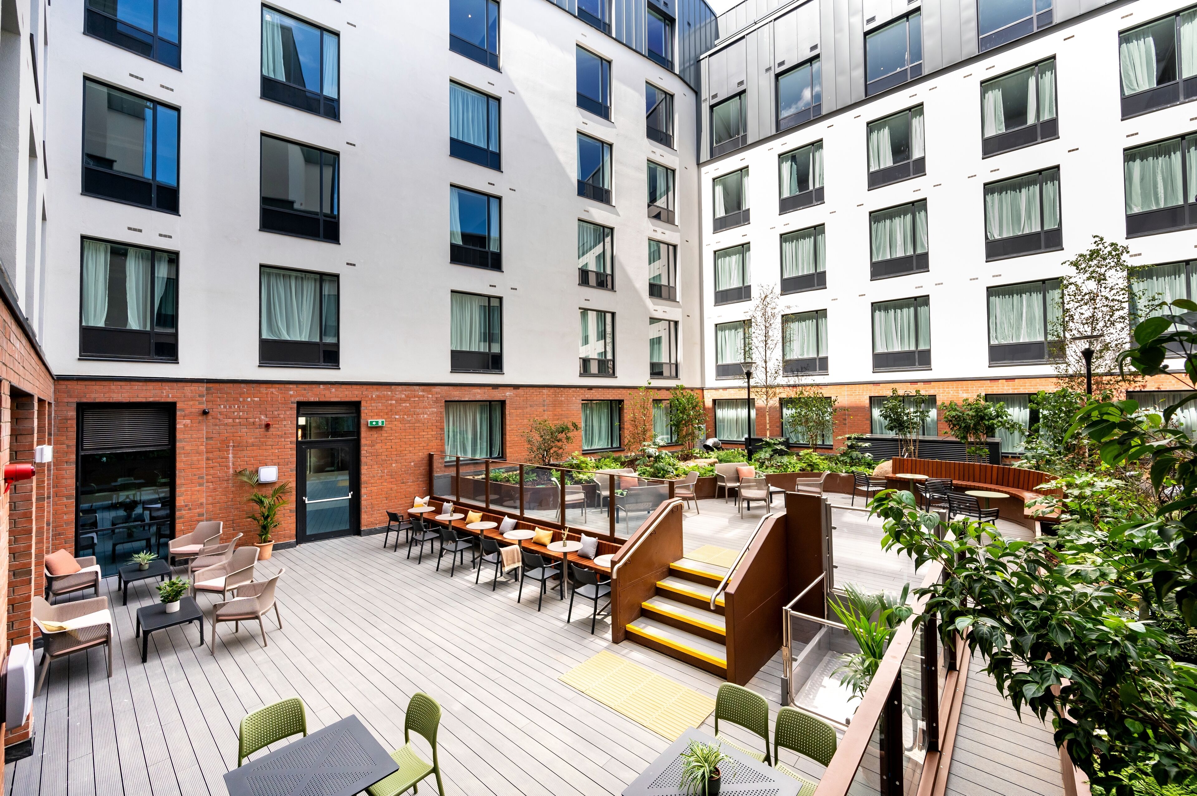 A modern outdoor patio area with seating and a staircase leading to an upper level.