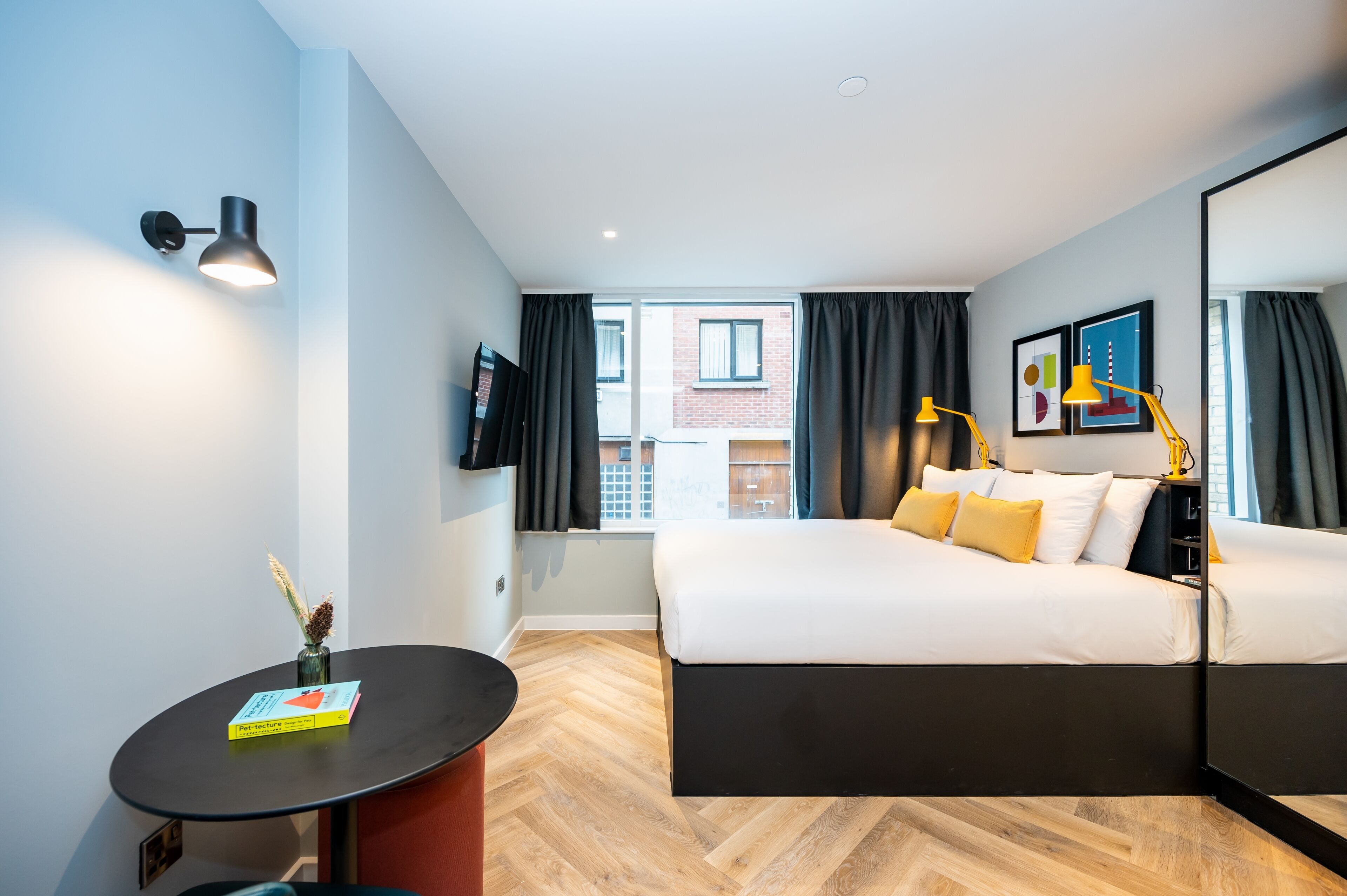 A modern hotel room with a large bed, a desk, and a view of the outside.