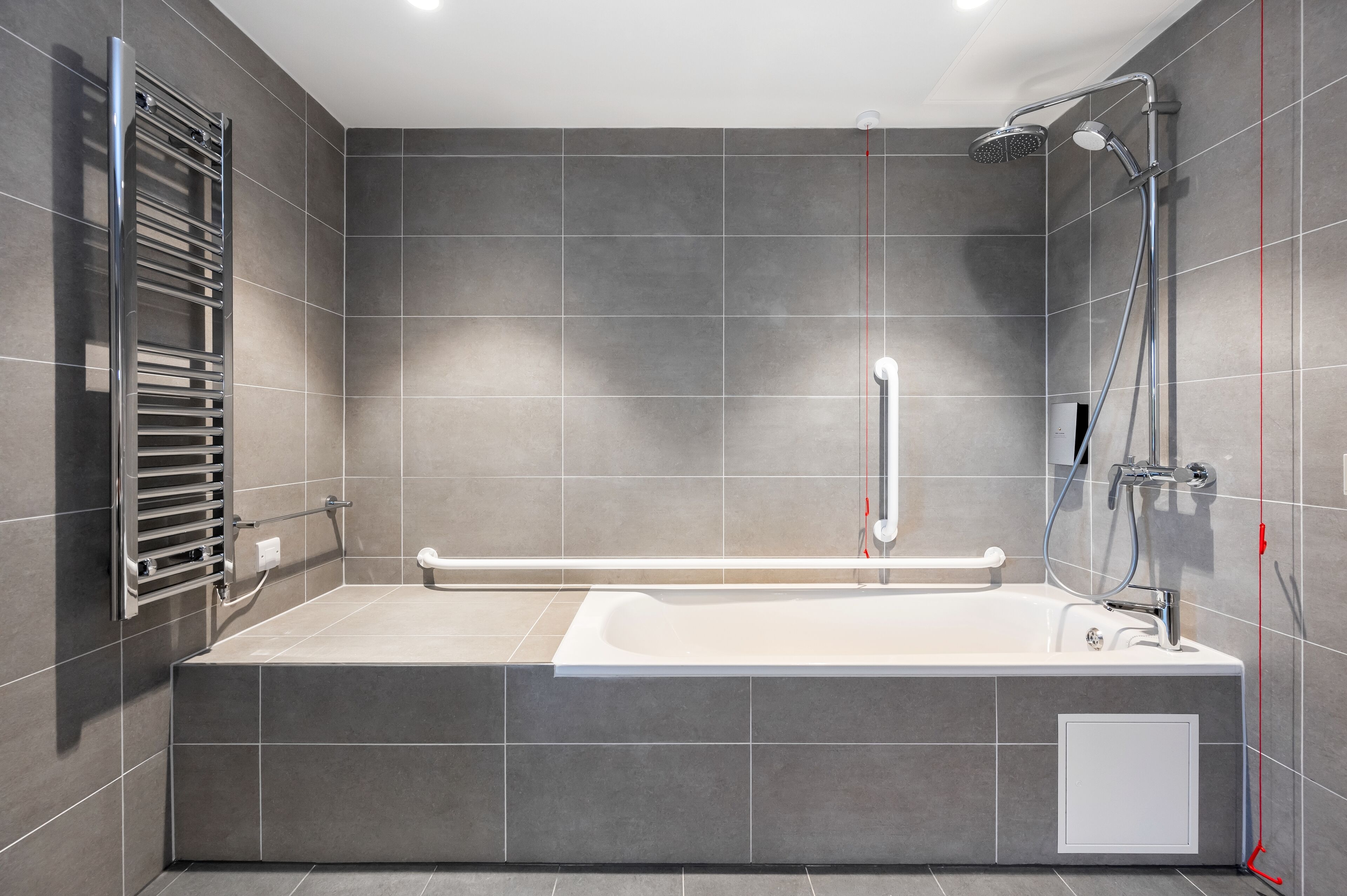 A modern bathroom with a large bathtub, a shower, and a towel rack.