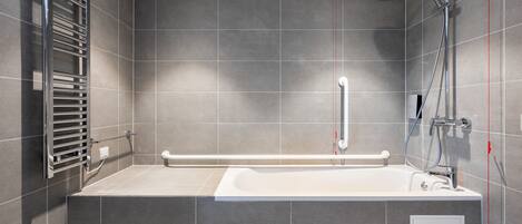 A modern bathroom with a large bathtub, a shower, and a towel rack.