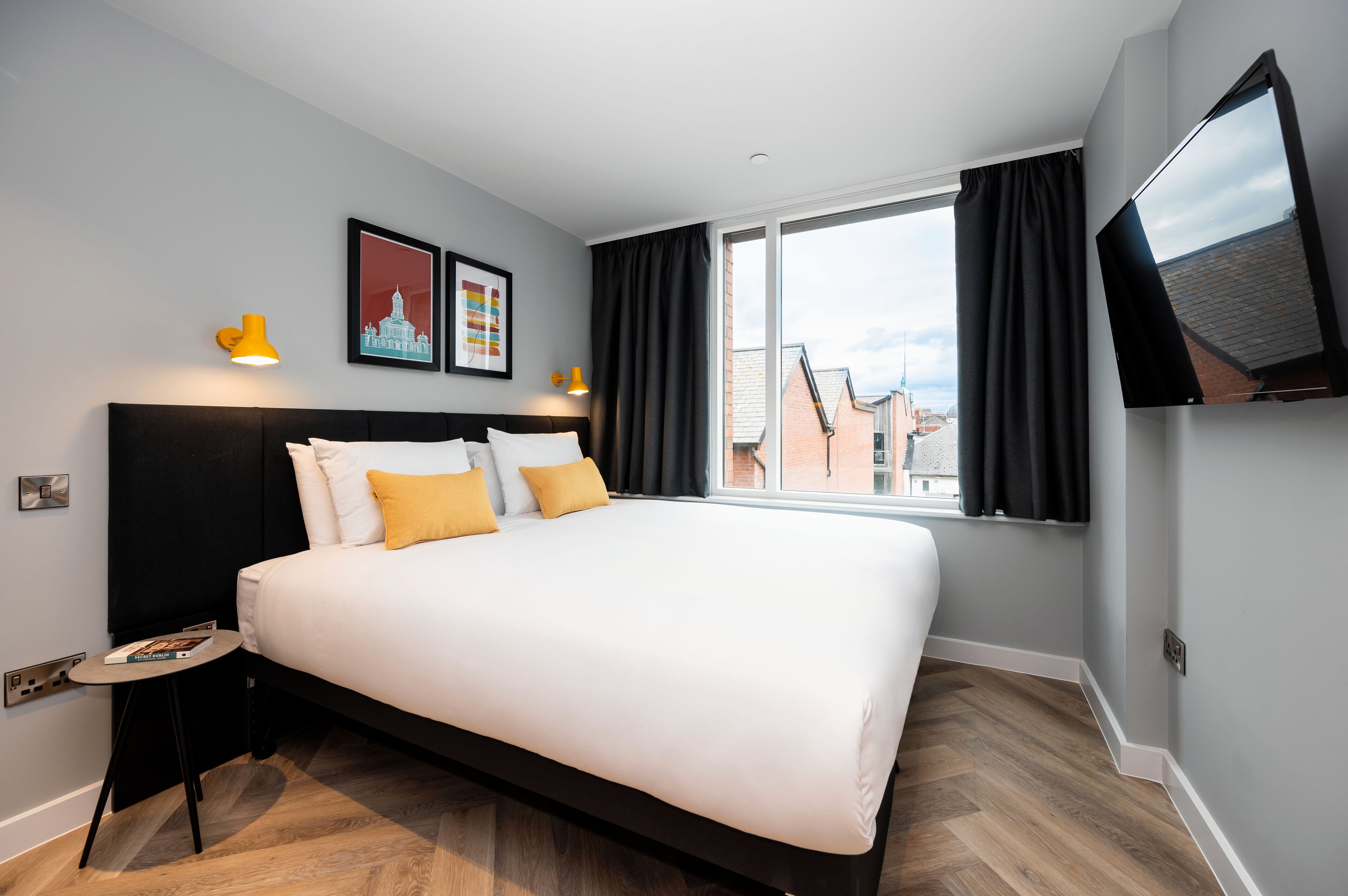 Et moderne hotelværelse med en stor seng, et fladskærms-tv og et vindue med gardiner.
