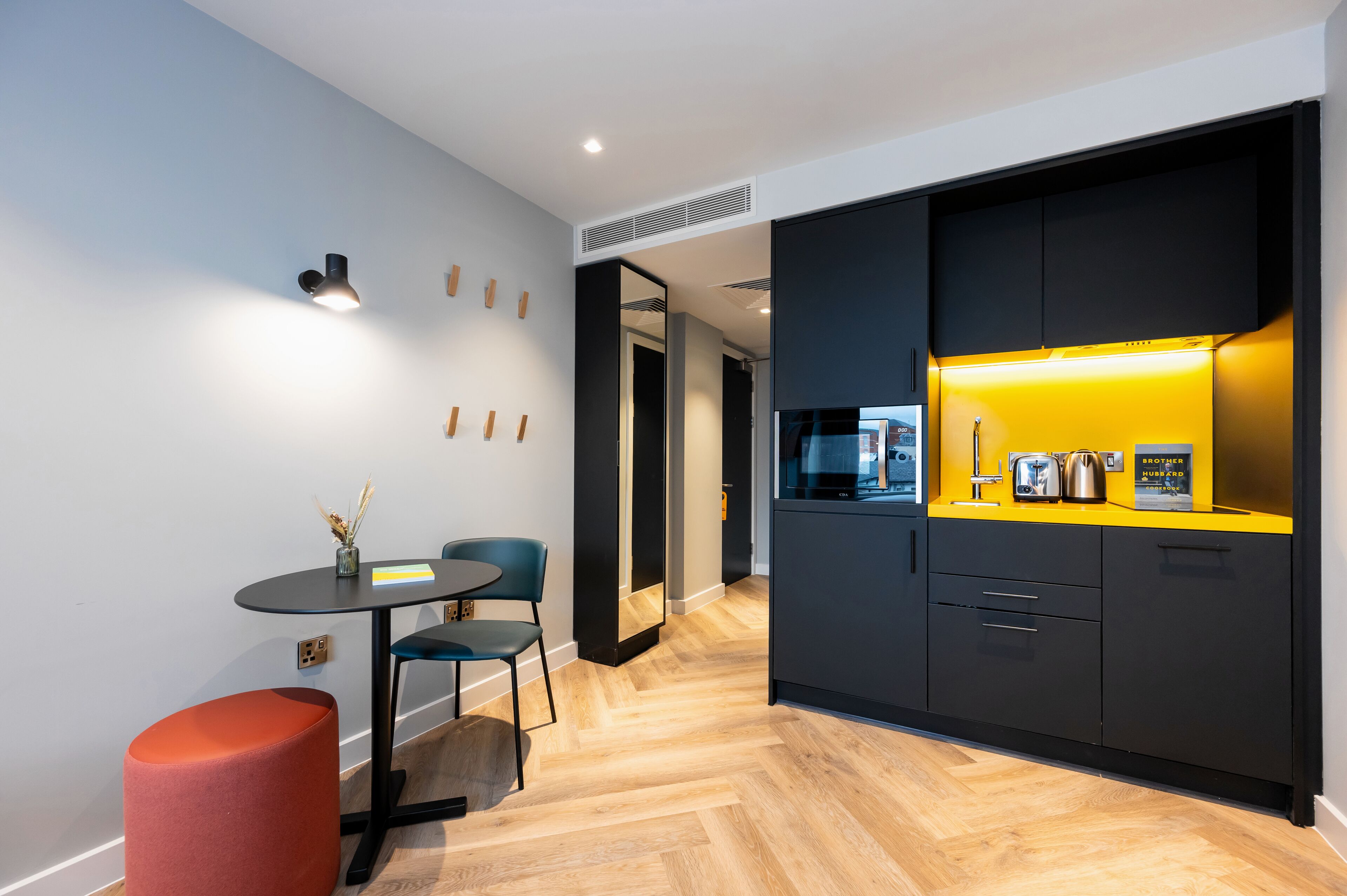 A modern kitchen with a yellow countertop, black cabinets, and a red accent chair.