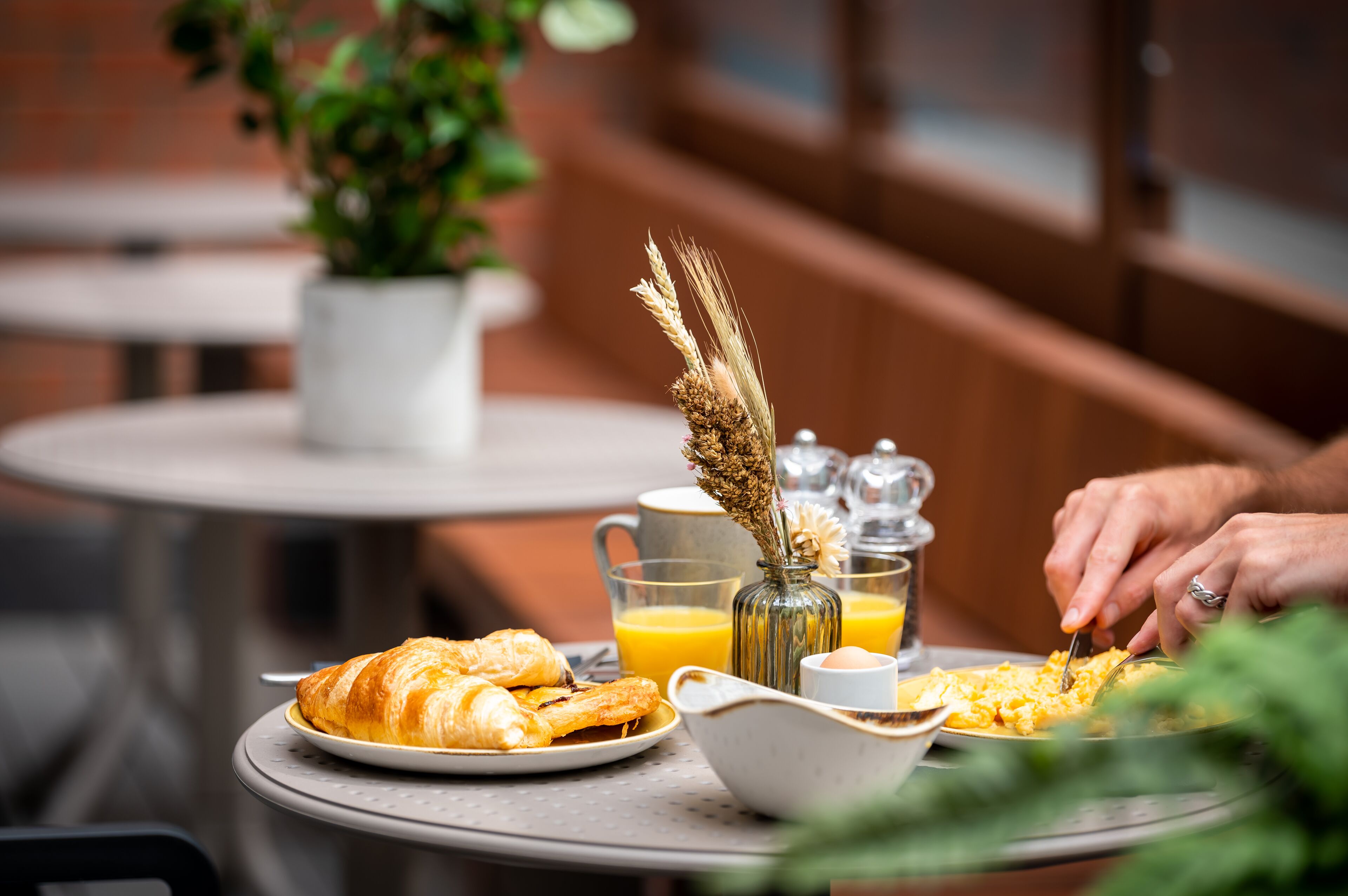 A breakfast table with croissants, scrambled eggs, and orange juice.