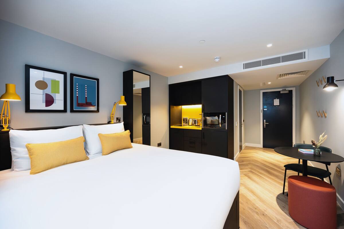 Une chambre d’hôtel moderne équipée d’un grand lit, d’un bureau et d’une kitchenette.