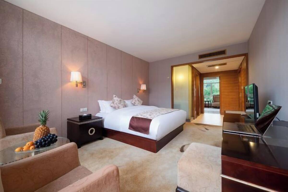 A hotel room with a bed, a desk, a chair, a nightstand, and a television.