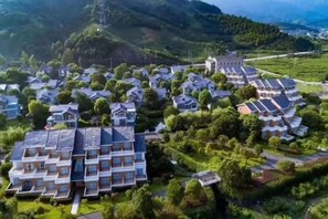 A residential area with multiple houses, some with solar panels, surrounded by greenery and hills. - Yinfeng Holiday Resort (Ningbo)