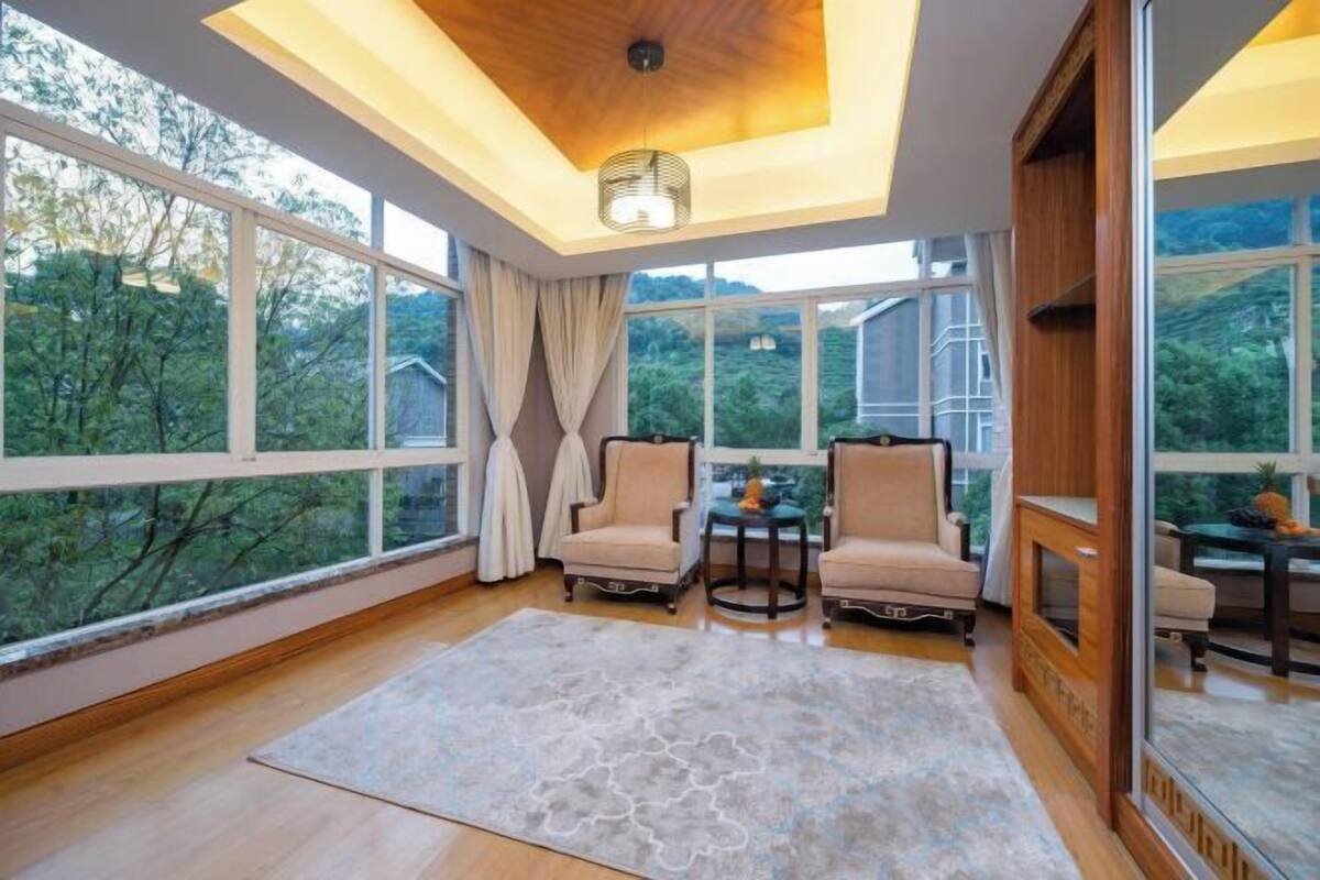 A spacious room with large windows, a wooden ceiling, and two chairs facing a small table.