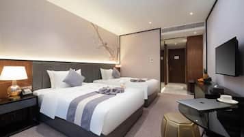 Una habitación de hotel moderna con dos camas, un escritorio, un televisor y un espejo.