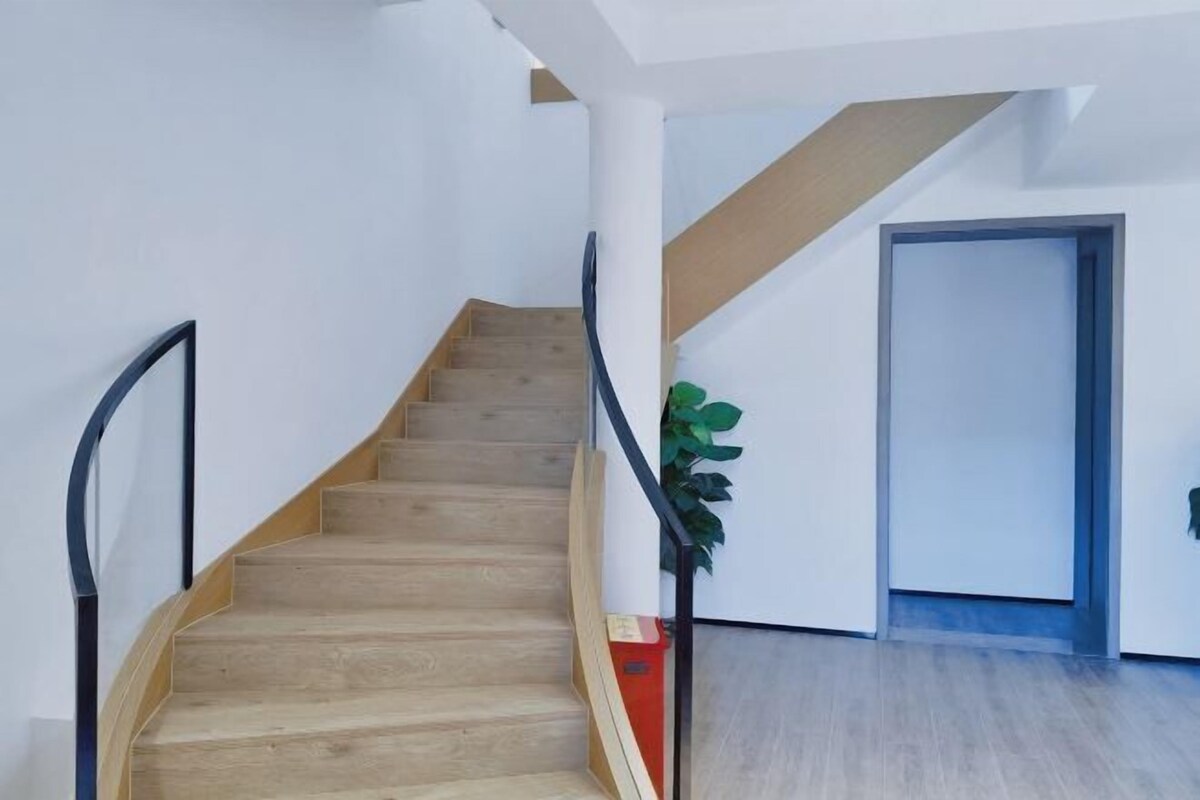 A staircase with wooden steps and black handrails, leading to a door.