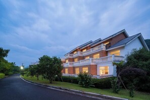 A multi-story building with a brick facade, multiple balconies, and a well-maintained lawn. - Yinfeng Holiday Resort (Ningbo)
