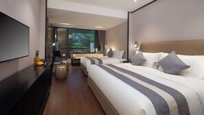 Habitación de hotel moderna con una cama grande, televisión, escritorio con silla y vistas a zonas verdes.