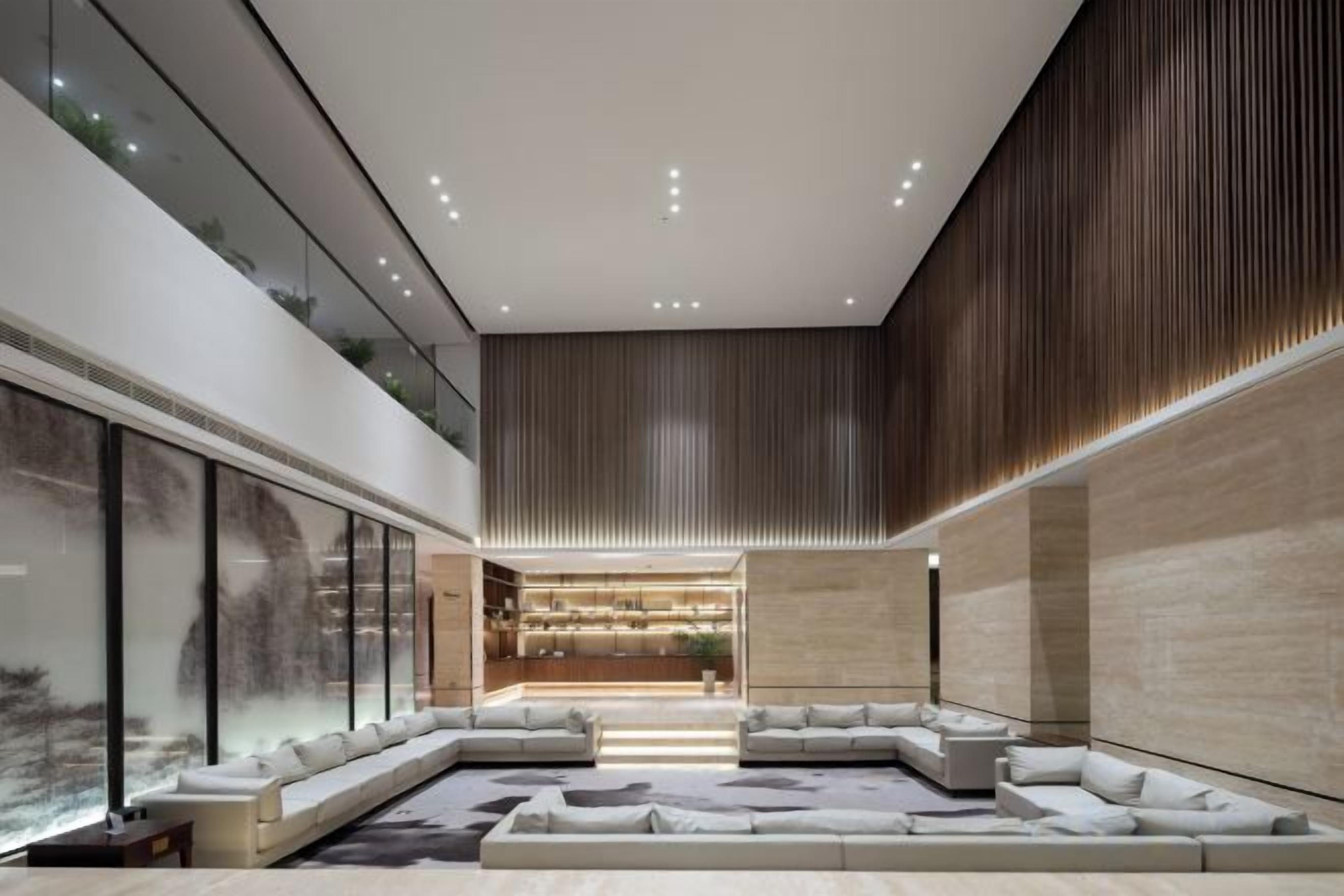 Un interior moderno con un amplio sofá modular, una pared de vidrio y un revestimiento de madera en listones.