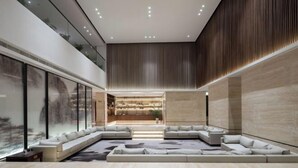 Un interior espacioso y moderno con un amplio salón, una cocina al fondo y un techo alto con iluminación empotrada.