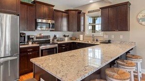 Una cocina con alacenas de madera oscura, electrodomésticos de acero inoxidable, encimera de granito y una ventana con vistas.