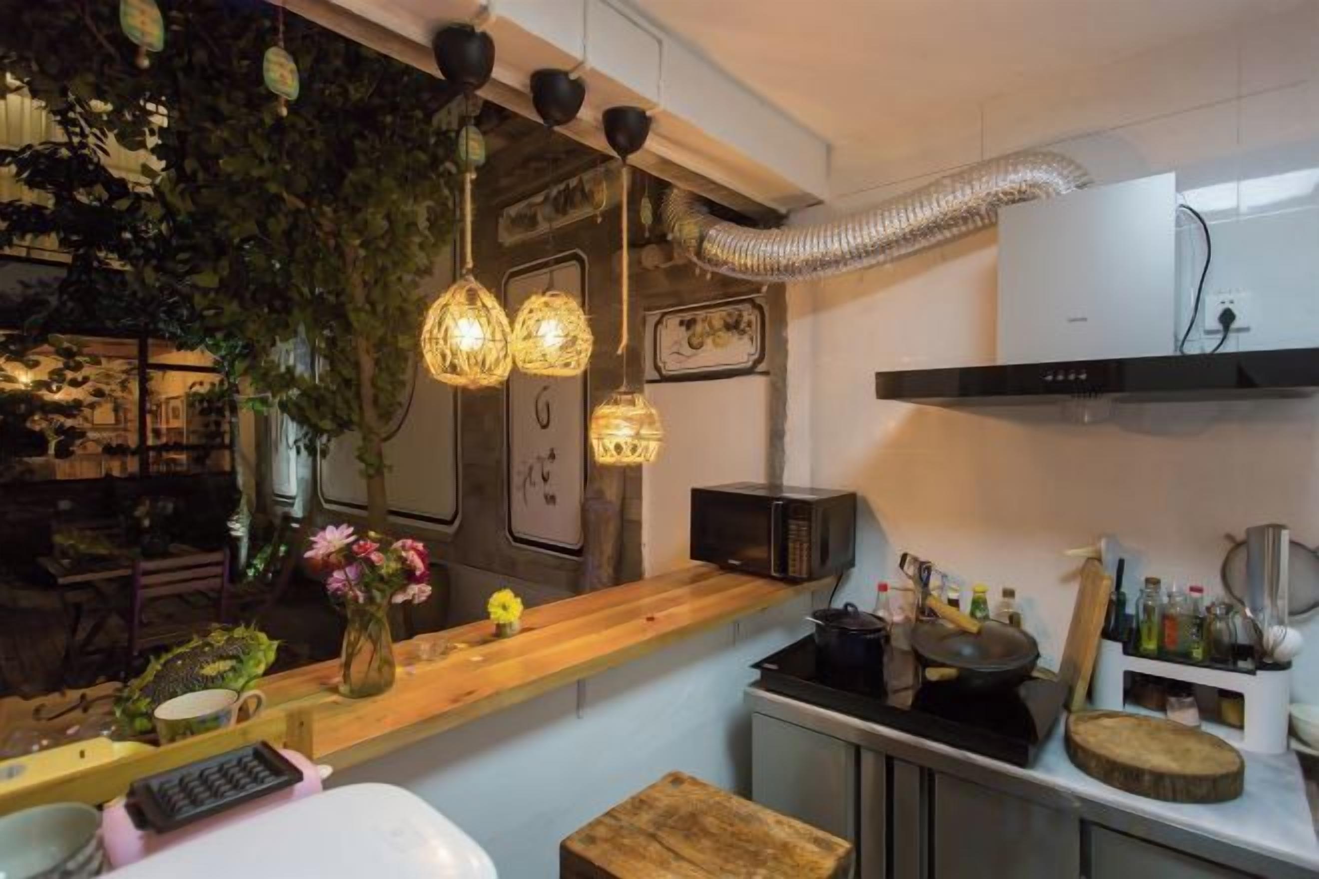 Una cocina con encimera de madera, luces colgantes y vistas al exterior.
