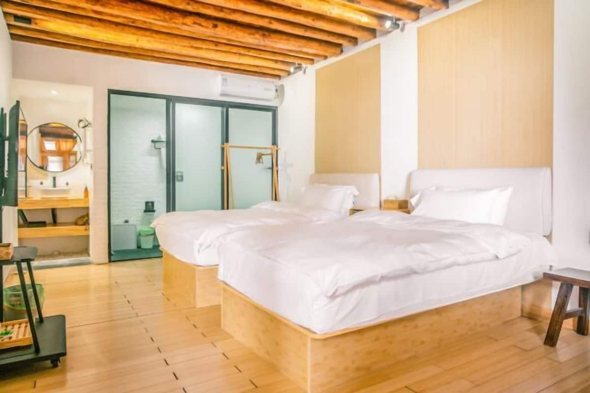 A modern hotel room with a wooden ceiling, a large bed with white bedding, a bedside table, and a mirror.
