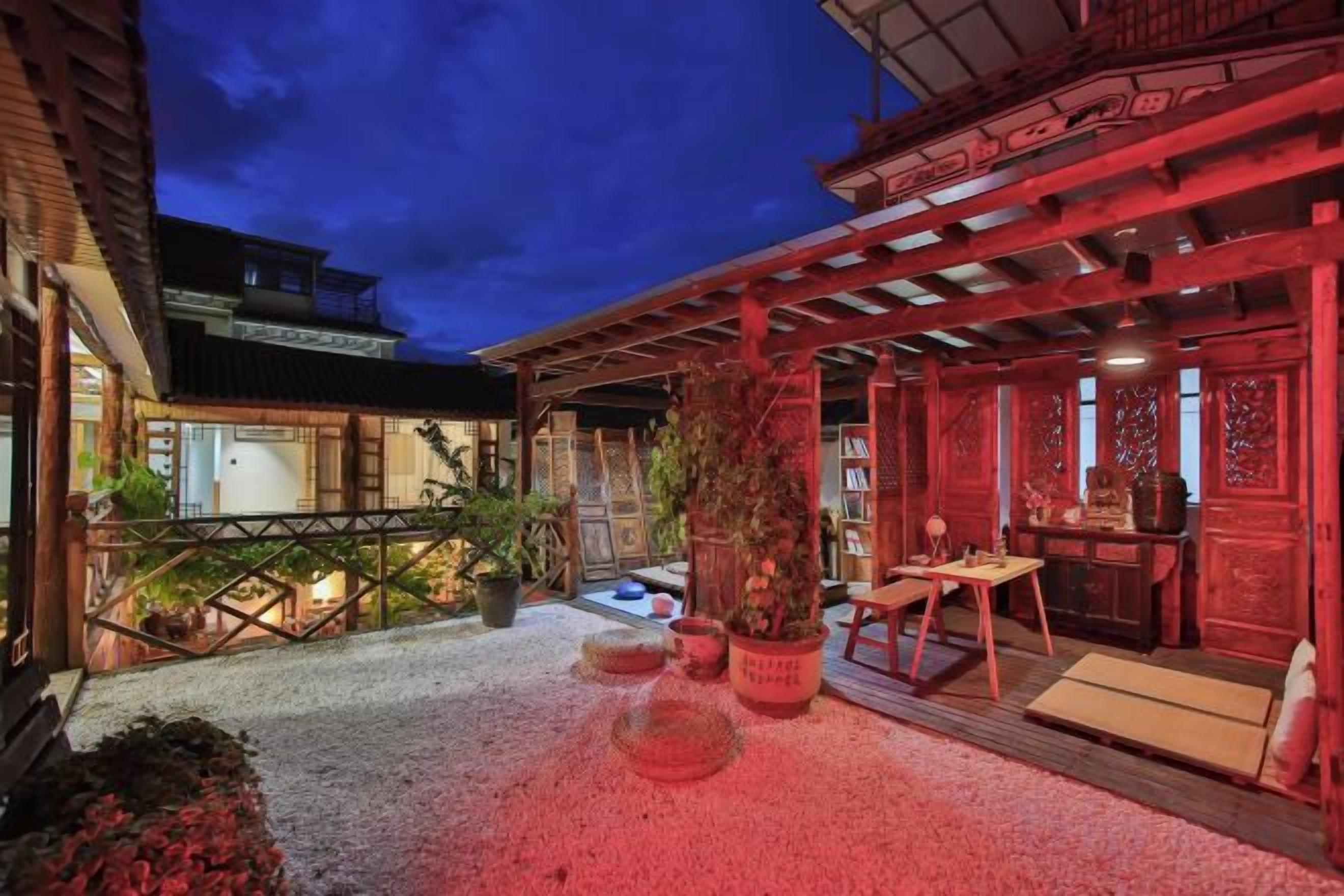 Un bâtiment de style japonais traditionnel, doté d’un espace extérieur aménagé avec des sièges, de structures en bois et des plantes en pot.