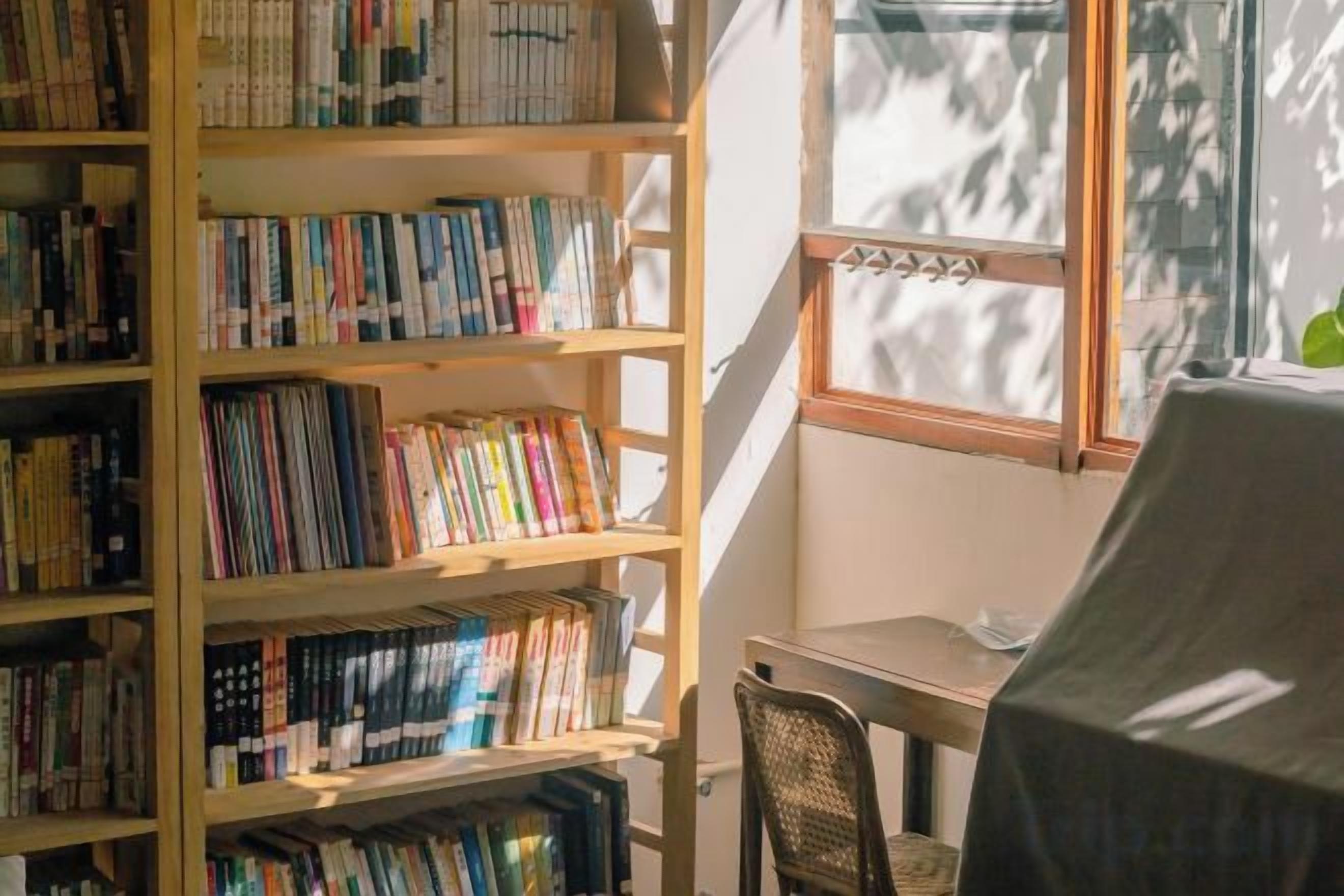 Una habitación con una estantería llena de libros, un escritorio y una silla.
