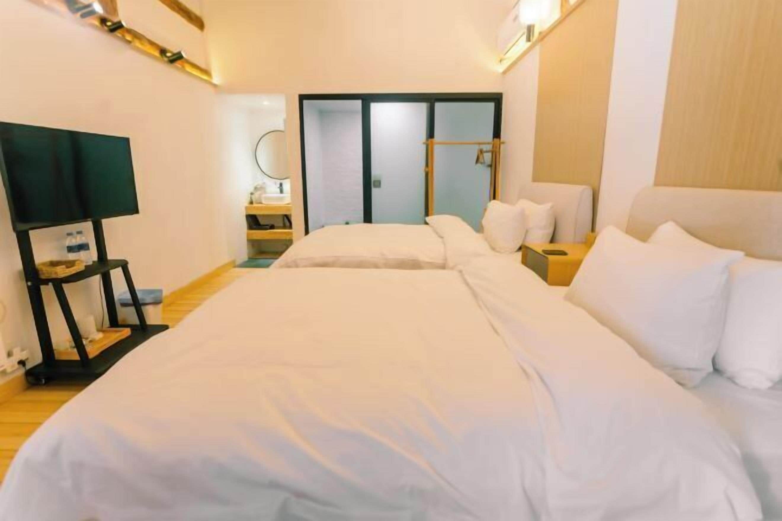 A hotel room with a large bed, a bedside table with a lamp, a wardrobe, and a mirror.