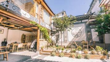 Une cour dotée d’une pergola en bois, d’un espace salon et de plantes en pot.