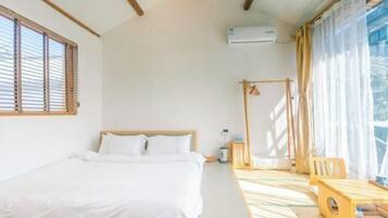 Una habitación con cama, una mesita, una silla y una ventana con persianas.
