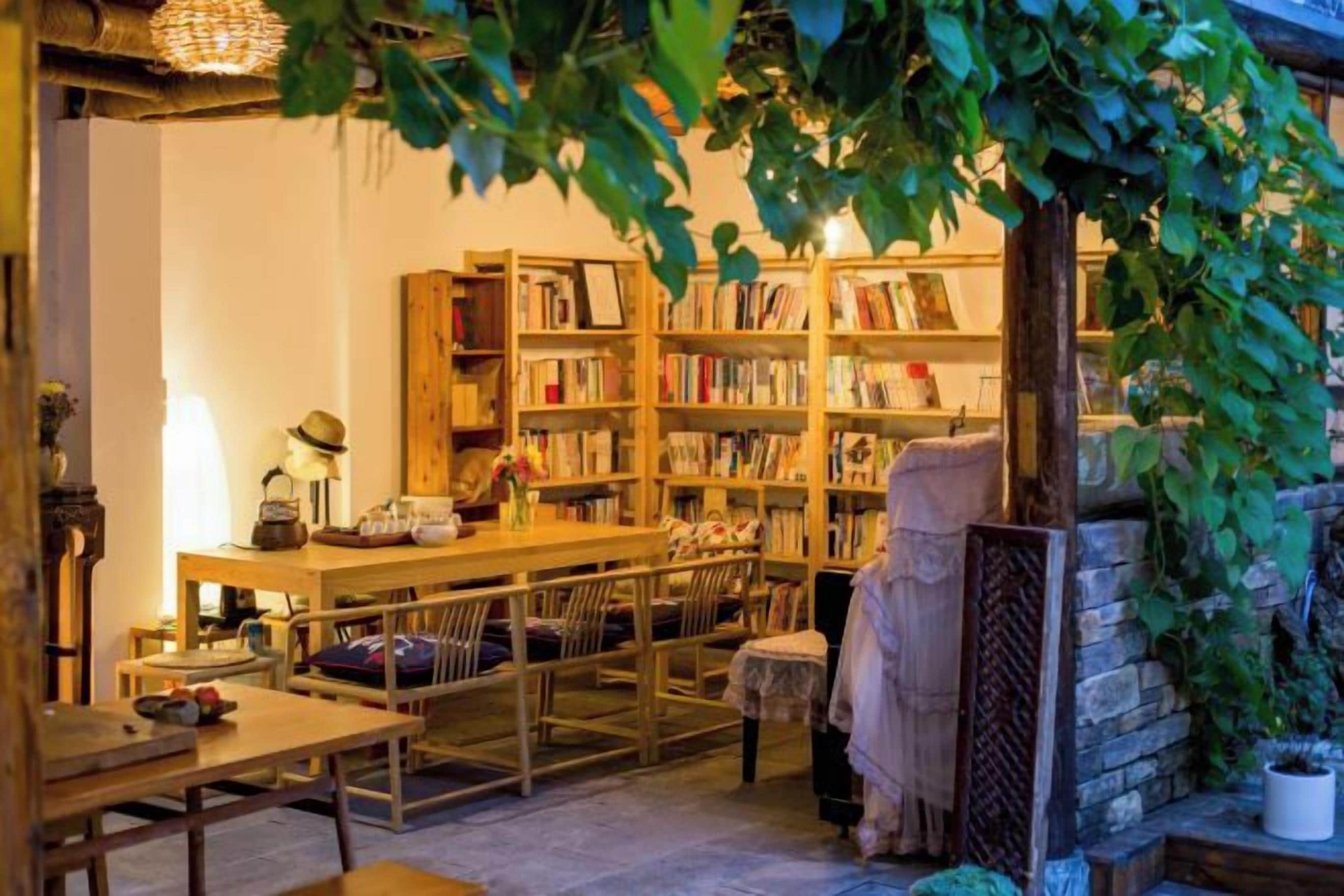 Un rincón acogedor para leer con una mesa de madera, sillas y una estantería llena de libros.