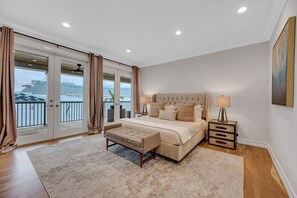 A spacious bedroom with a large bed, a bedside table, a nightstand, and a view of a cruise ship through the sliding glass doors. - Million Dollar Views / Private beach / Heated pool / Walk to Beach / Harbourview Key | VlLLAS (Fort Lauderdale)