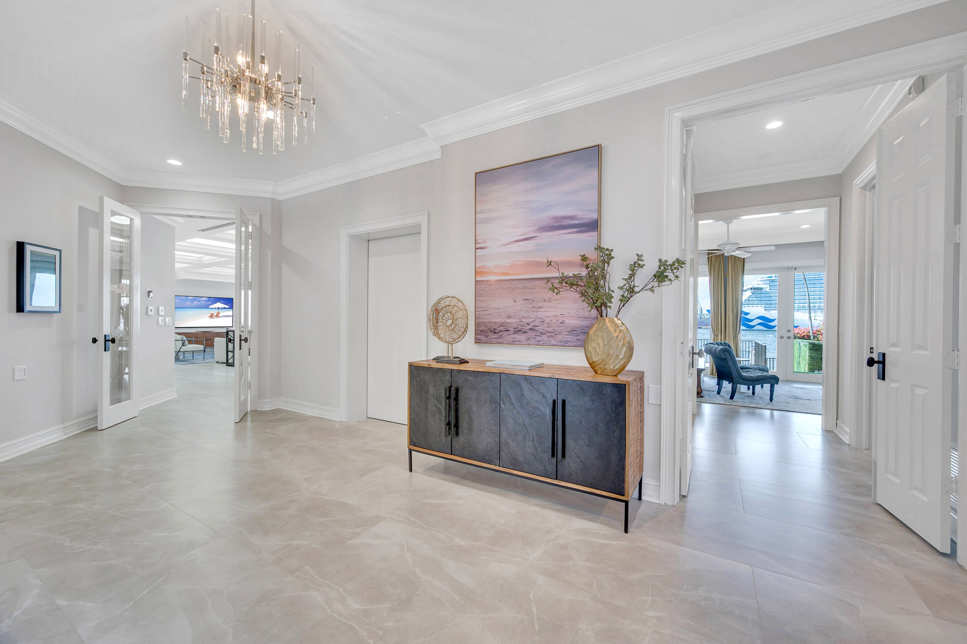 A spacious hallway with a modern console table, a large painting, and a chandelier.