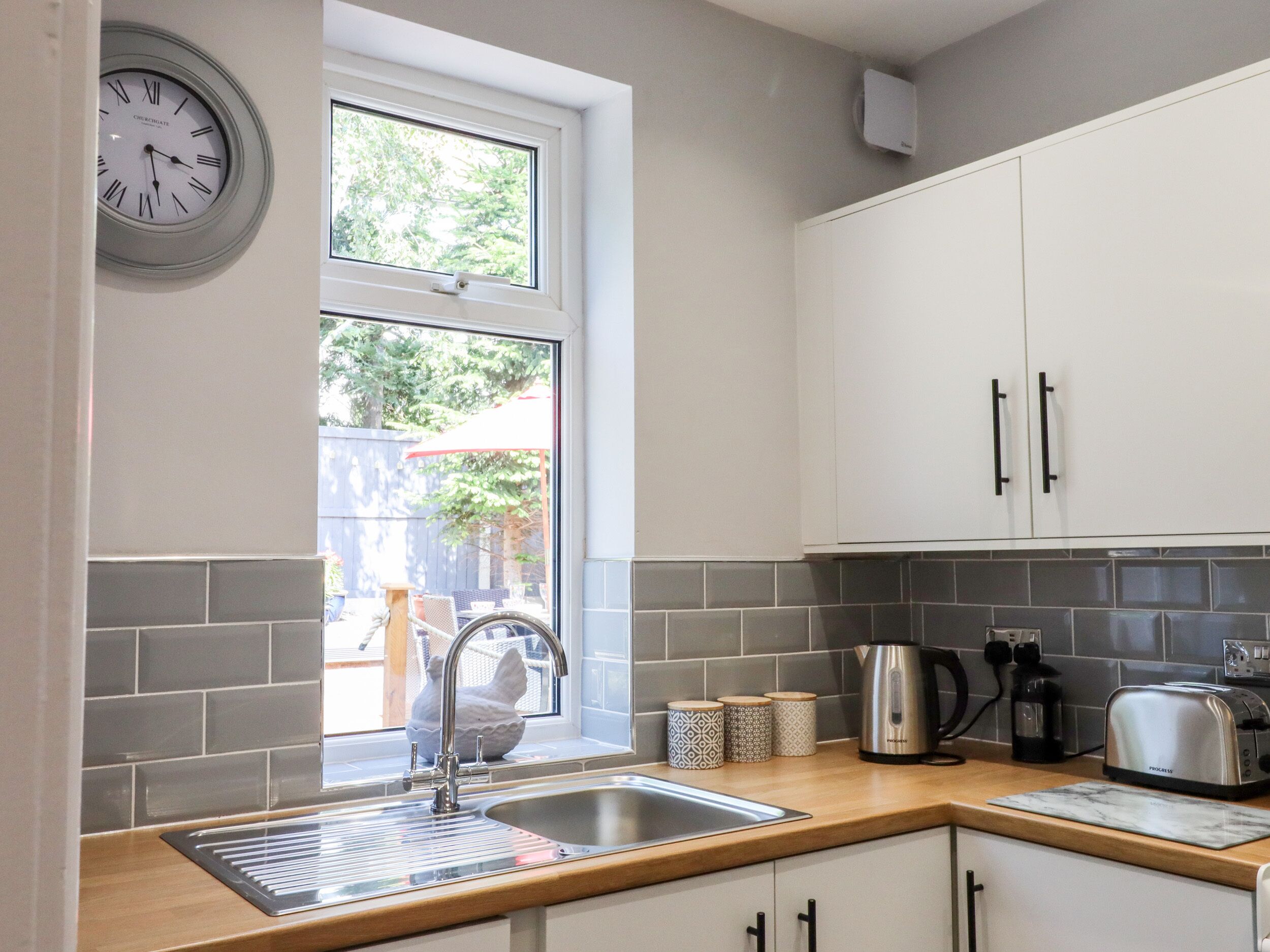 A modern kitchen with a sink, countertop, cabinets, and a window.