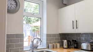 A modern kitchen with a sink, countertop, cabinets, and a window. - 13 The Crescent (Colwyn Bay)