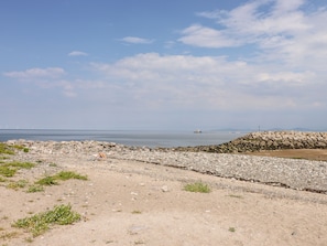 A rocky beach with a stone wall and a calm sea in the background.