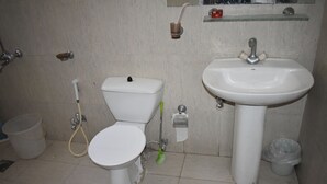 A bathroom with a toilet, sink, and shower. - Hotel 1947 (Gilgit)