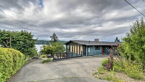 Ein modernes Haus mit befestigter Auffahrt, einer kleinen Veranda und Seeblick.
