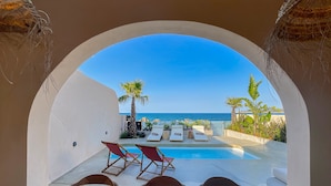An arched view of a pool area with lounge chairs and a view of the sea. - Kaliva Residence (Apokoronas)