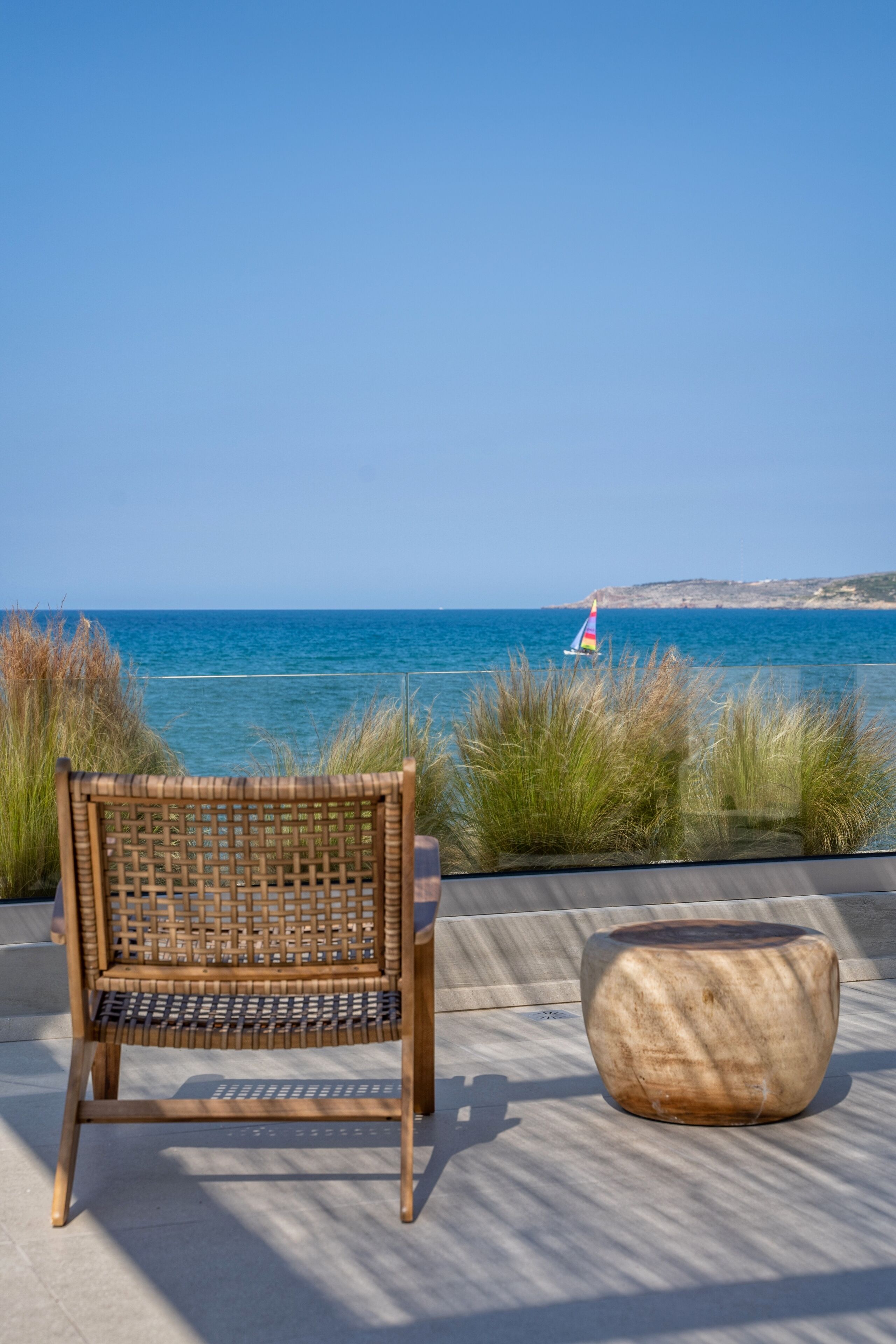 A wooden bench and a stone planter by a coastal view.