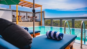 A poolside area with lounge chairs, a pergola, and a view of the water. - Maa Thundi (Fuvahmulah)