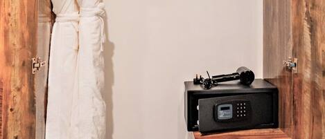 Un vestidor con puerta de madera, una bata colgada en un perchero, un radio negro y un par de zapatillas en el suelo.