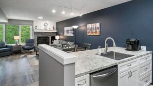 Una cocina moderna con encimera de granito, armarios blancos y lavavajillas integrado.