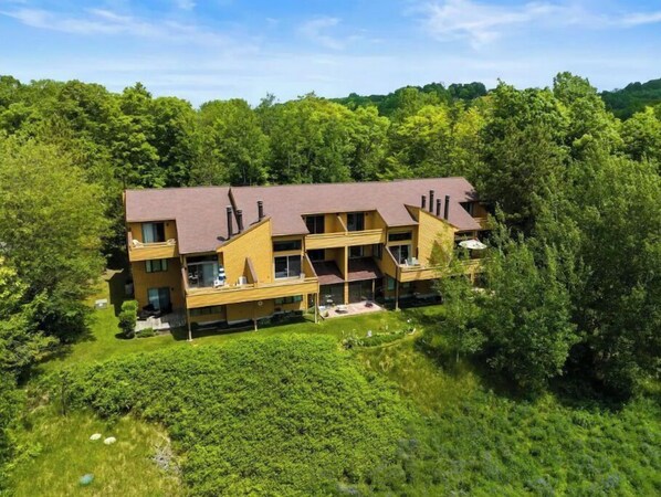 A multi-story building with a brown roof, surrounded by dense green trees. - Trout Creek Resort/Golf/Beaches/Pools/Hot tub/Sauna/Pet friendly (Harbor Springs)