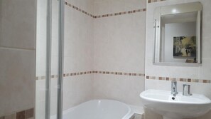 Une salle de bain avec une baignoire, un lavabo et une douche.
