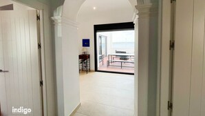 A hallway with white walls and a tiled floor leading to a balcony with a table and chairs. - Apartment 4 bedrooms Center of Ayamonte with stunning Views DEK01 (Ayamonte)