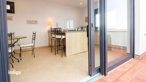 A modern kitchen with a dining area, featuring a bar counter, chairs, and a table. - Apartment 4 bedrooms Center of Ayamonte with stunning Views DEK01 (Ayamonte)
