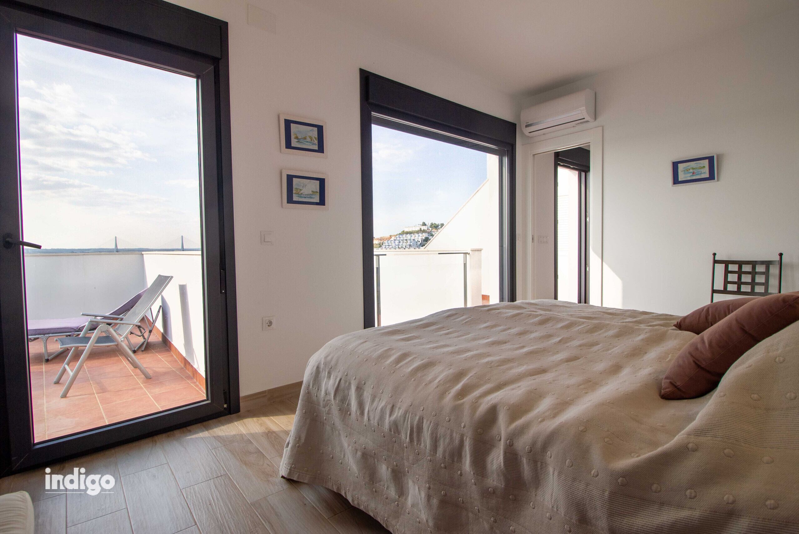 Ein Schlafzimmer mit Bett, Sessel und Balkon mit Aussicht.